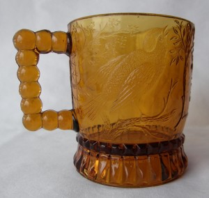 Bird on a Branch (Size: 2-7/8" dia. x 3-3/8" ht.; Color: Amber) To the right of the handle, the sculpting shows an upright singing bird perched on a branch.